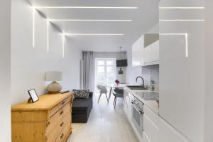 a kitchen with white cabinets and a dining room at Apartament 200 Apartamenty No.1 Ogród, parking w Centrum in Szczecin