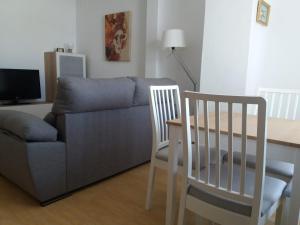 uma sala de estar com um sofá, uma mesa e cadeiras em Ático en el centro con terraza em Cádis