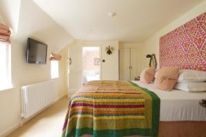 a bedroom with a bed and a television at The Bay Tree Hotel in Burford