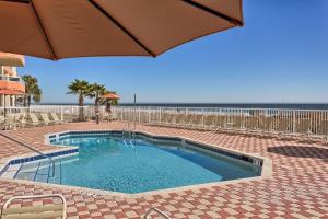 a swimming pool with an umbrella next to the beach at Enclave 304 in Orange Beach