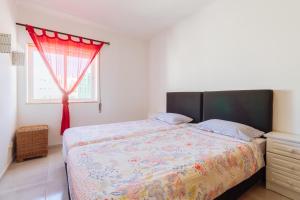 アルマカオ・デ・ペラにあるApartment Dean direkt am Meerのベッドルーム1室(赤いカーテンと窓付きのベッド1台付)