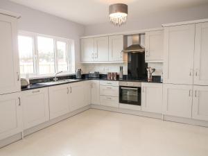 a white kitchen with white cabinets and a chandelier at Culmore Point in Culmore