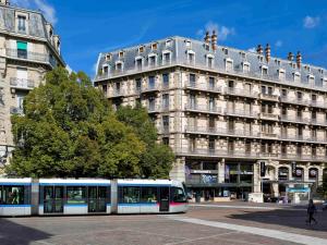 eine Straßenbahn vor einem großen Gebäude in der Unterkunft ibis Grenoble Centre Bastille in Grenoble