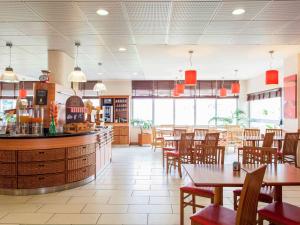 um restaurante com mesas e cadeiras e um bar em Hotel ibis Lisboa Jose Malhoa em Lisboa
