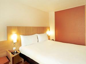 1 dormitorio con 1 cama grande con almohadas blancas en Hotel ibis Lisboa Jose Malhoa, en Lisboa