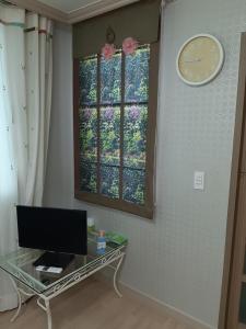 Pokój z telewizorem i zegarem na ścianie w obiekcie Chungaram w mieście Damyang