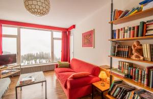 a living room with a red couch and bookshelves at Viktoria B32 by Arosa Holiday in Arosa