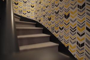 a staircase in a room with a patterned wall at Logis Hotel Le Chêne Vert in Savenay