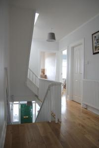 a white staircase in a white room with wooden floors at Greenmount Bed and Breakfast in Belfast