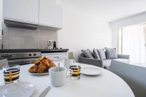 a white kitchen with a table with a plate of croissants at Bright One BDRM Apartment AC-Congress, Beaches by Olidesi in Cannes