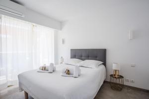 a white bedroom with a large white bed with two towels at Bright One BDRM Apartment AC-Congress, Beaches by Olidesi in Cannes