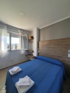 a bedroom with a blue bed with two towels on it at Pensi&oacute;n Portomi&ntilde;o in Portomarin