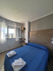 a bedroom with a blue bed with two towels on it at Pensión Portomiño in Portomarin