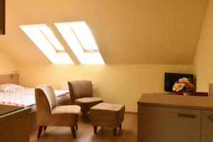 a bedroom with two chairs and a bed with a skylight at Vendelin Apartmany in Bojnice