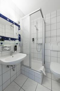 a white bathroom with a sink and a shower at Hotel Ostseewoge in Graal-Müritz