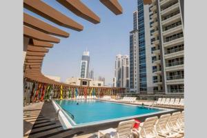 a large swimming pool with white chairs and buildings at HiGuests - Roomy Apt With Infinity Pool Close to Burj Khalifa in Dubai