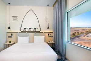 um quarto com uma cama e uma grande janela em Swiss-Belinn Airport Muscat Oman em Mascate