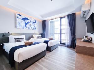 バンコクにあるSOVA Hotel Bangkokのベッド2台とテレビが備わるホテルルームです。