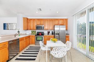 a kitchen with wooden cabinets and a white table and chairs at Updated Vista Cay Townhome, 10 min from Universal in Orlando