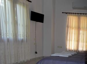 a bedroom with a bed and a television and curtains at Pine tree house in Troulos