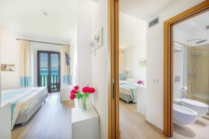 a bathroom with two beds and a tub and a sink at Hotel Dei Pini in Alghero