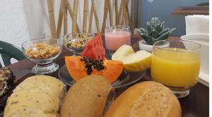 a tray of food with bread and fruit and drinks at Joaquina Beach Hotel in Florianópolis