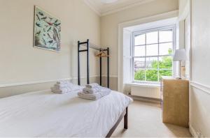 a white bedroom with a bed with towels on it at New Town Apartment with Castle View in Edinburgh