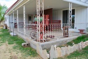 une terrasse couverte à l'avant d'une maison avec une clôture dans l'établissement Dora's Country Cottage, à Escalante