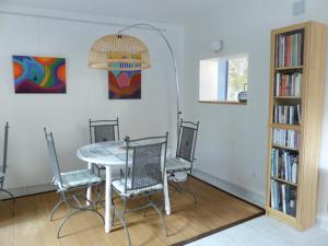 a dining room with a table and chairs and a book shelf at Le chant des arbres in Bourron-Marlotte