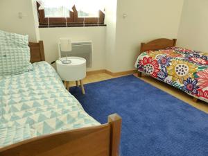 - une chambre avec 2 lits et un tapis bleu dans l'établissement Le chant des arbres, à Bourron-Marlotte