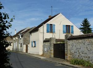 a row of houses with blue windows on a street at Le chant des arbres in Bourron-Marlotte
