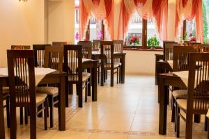 a restaurant with wooden tables and chairs and windows at Hotel Esprit in Braşov