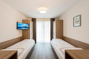 Pokój z dwoma łóżkami i telewizorem na ścianie w obiekcie CIMA 11 & SASS PORDOI - Apartments w mieście Moena