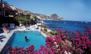 un gruppo di persone in una piscina vicino all'oceano di Hotel Casa Rosa Terme a Ischia