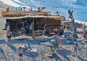 a group of people on a beach with umbrellas at Xinara House Old Blacksmiths in Tripótamos