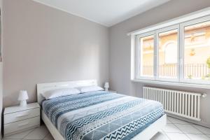 a white bedroom with a bed and a window at Lido Apartments by Quokka 360 - 5 min from the centre and the Lugano Lido in Lugano
