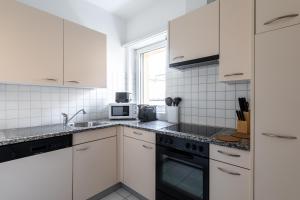 a white kitchen with white cabinets and a sink at Lido Apartments by Quokka 360 - 5 min from the centre and the Lugano Lido in Lugano