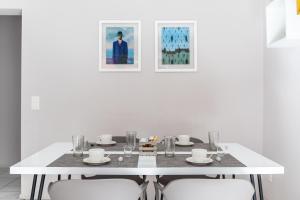 a white dining room table with white chairs and paintings at Lido Apartments by Quokka 360 - 5 min from the centre and the Lugano Lido in Lugano