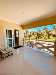 a room with a balcony with a view of palm trees at Casa em flecheiras com piscina in Flecheiras