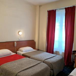 パリにあるホテル リバティのベッド2台と窓が備わるホテルルームです。