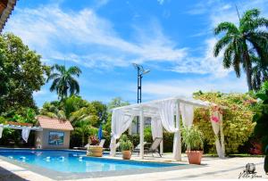 a white gazebo next to a swimming pool at Auberge Villa Cana in Cap-Haïtien