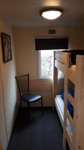 een slaapkamer met een stapelbed, een stoel en een raam bij Comfortabel 4-persoons chalet (airco + fietsen) op Recreatiepark Eikenhof in Paasloo
