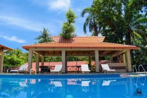 - une piscine avec un kiosque et des chaises à côté dans l'établissement Auberge Villa Cana, à Cap-Haïtien