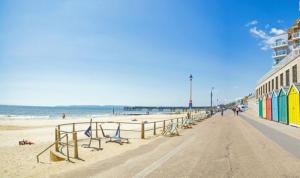 a beach with a building and chairs on the sand at Brooklands Lodge in Bournemouth