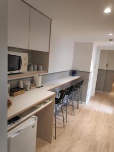 a kitchen with white cabinets and bar stools at Hostal BESTPRICE Barcelona Stadium in Barcelona