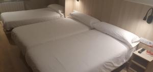 a bed with white sheets and pillows in a room at Hostal Conde Güell in Barcelona