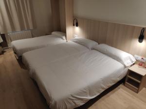 2 camas en una habitación de hotel con sábanas blancas en Hostal Conde Güell en Barcelona
