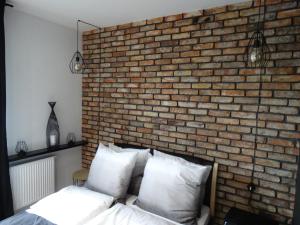 sypialnia z ceglaną ścianą i łóżkiem z białymi poduszkami w obiekcie Black&White Apartment Bis - Małe Garbary 8 w Poznaniu