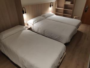 
two beds in a room with a white bedspread at Hostal Conde Güell in Barcelona
