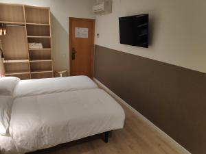 a room with two beds and a tv on the wall at Hostal Conde Güell in Barcelona